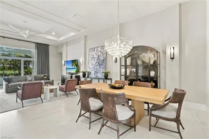 Open floor plan featuring coffered ceilings, large-format tile flooring, a tiered crystal chandelier, and a built-in arched display cabinet