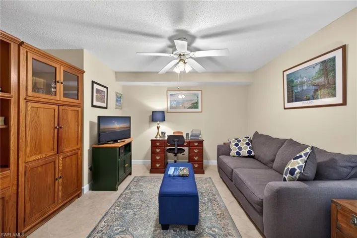 Living area featuring a textured ceiling, a ceiling fan, and a desk