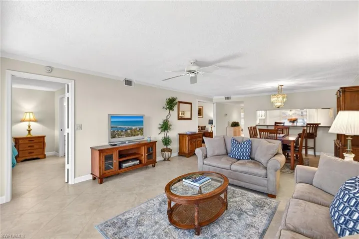 Living room with crown molding, ceiling fan, a textured ceiling, and suspended lighting