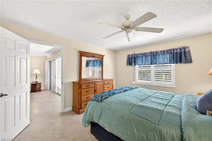 Bedroom with a ceiling fan, a textured ceiling, and tile patterned flooring
