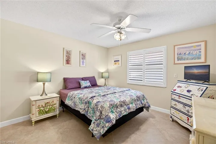 Bedroom featuring a ceiling fan, a textured ceiling, and light tile patterned flooring