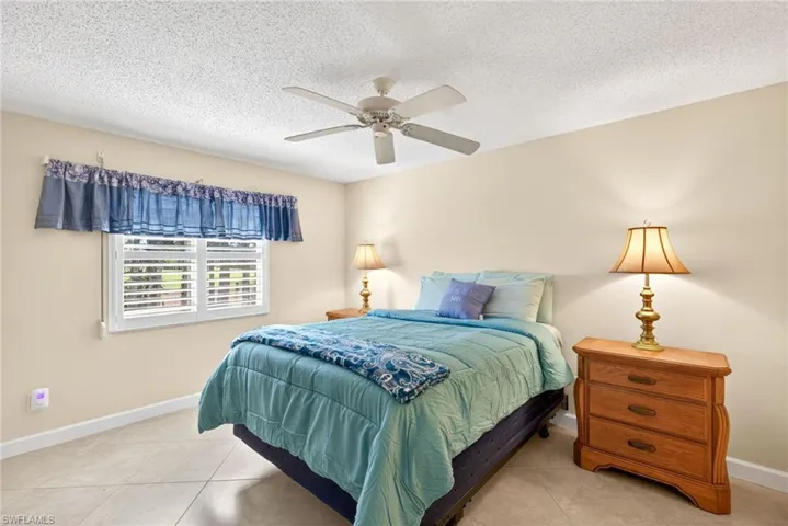 Tiled bedroom featuring a textured ceiling and ceiling fan