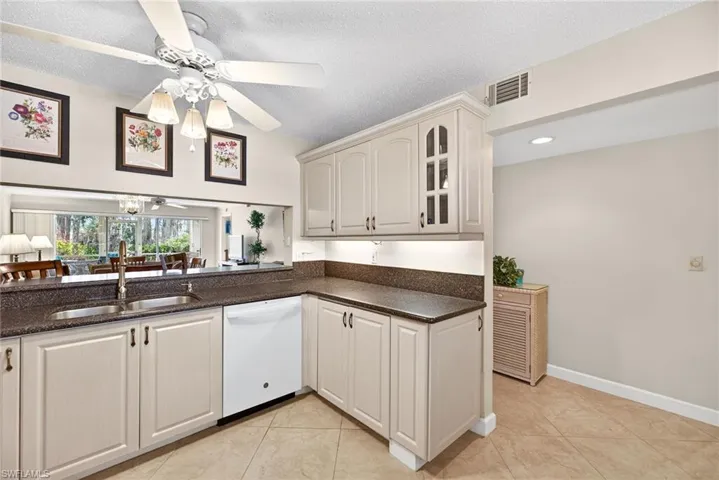 Kitchen featuring a ceiling fan, dishwasher, dark stone counters, a textured ceiling, and light tile patterned floors