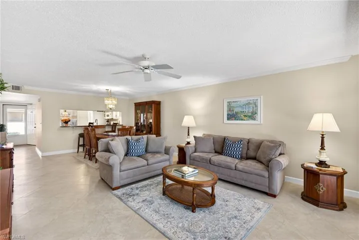 Living area with ceiling fan, ornamental molding, a textured ceiling, and light tile patterned flooring