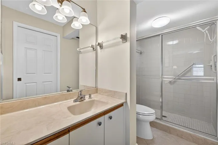 Full bathroom with a stall shower, vanity, and light tile patterned floors
