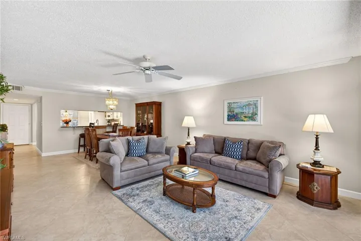Living room featuring ornamental molding, a ceiling fan, a textured ceiling, and light tile patterned floors