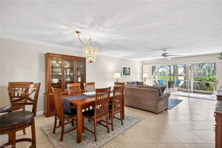 Dining space with a ceiling fan, suspended lighting, a textured ceiling, light tile patterned floors, and ornamental molding