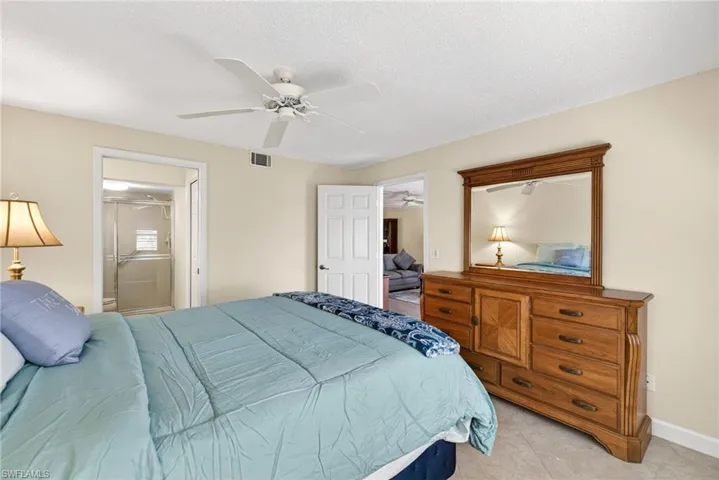 Bedroom with ensuite bath, a ceiling fan, and a textured ceiling