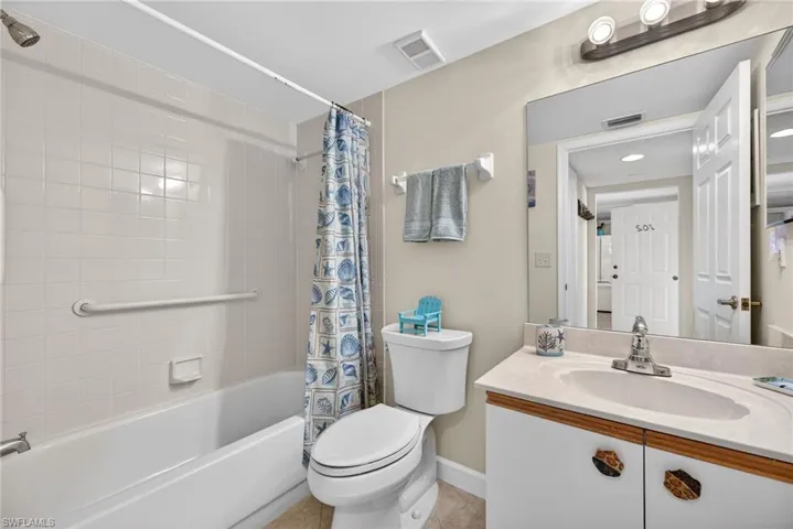 Bathroom with vanity, shower / bath combo with shower curtain, and light tile patterned flooring