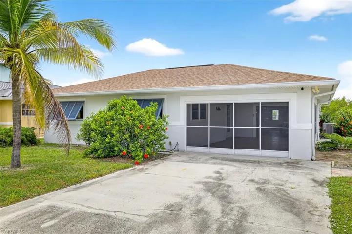 Back of property featuring a lawn, a shingled roof, and stucco siding