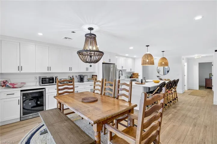 Dining area with wine cooler, recessed lighting, light wood finished floors, and a chandelier