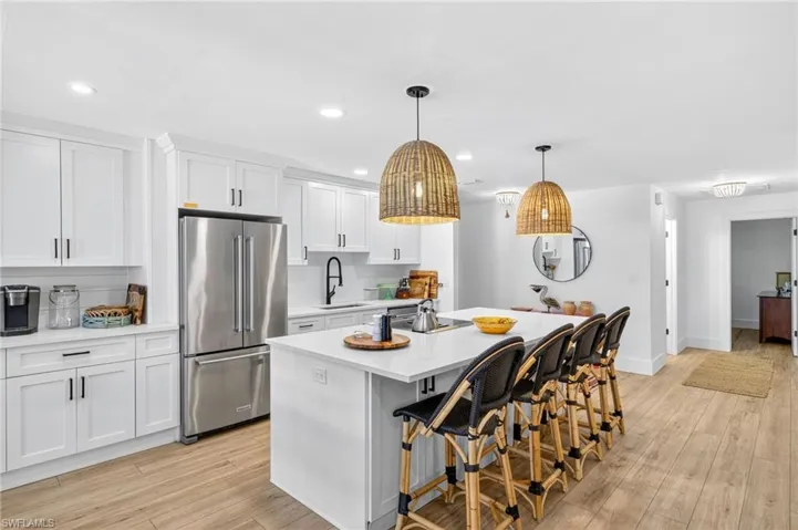 Kitchen with freestanding refrigerator, a kitchen breakfast bar, light wood-type flooring, a kitchen island with sink, and recessed lighting