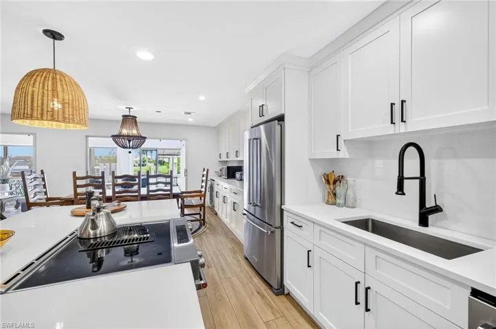 Kitchen featuring white cabinetry, high end refrigerator, hanging light fixtures, recessed lighting, and tasteful backsplash