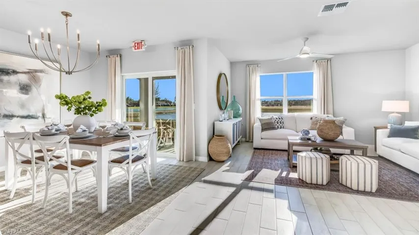 Model home. Living room featuring a ceiling fan, wood finish floors, suspended lighting, and a water view