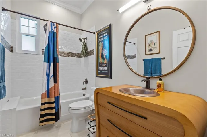 Updated full bathroom featuring tile patterned flooring, crown molding, toilet, vanity, and shower / tub combo