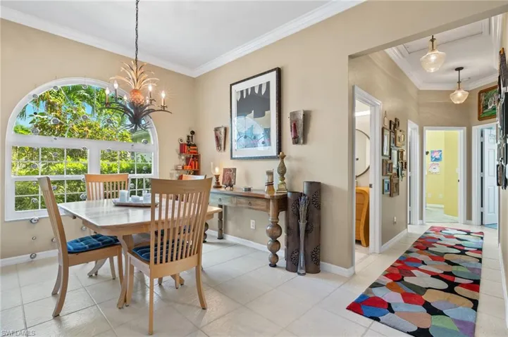 Dining room featuring a notable chandelier, light tile patterned floors, and crown molding. Updated light fixers in hallway.