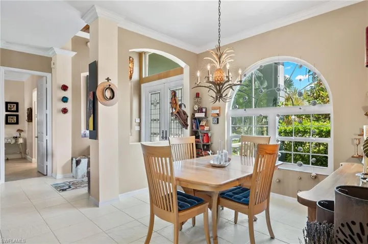 Formal dining space with decorative columns, a notable chandelier, crown molding, and a wealth of natural light.