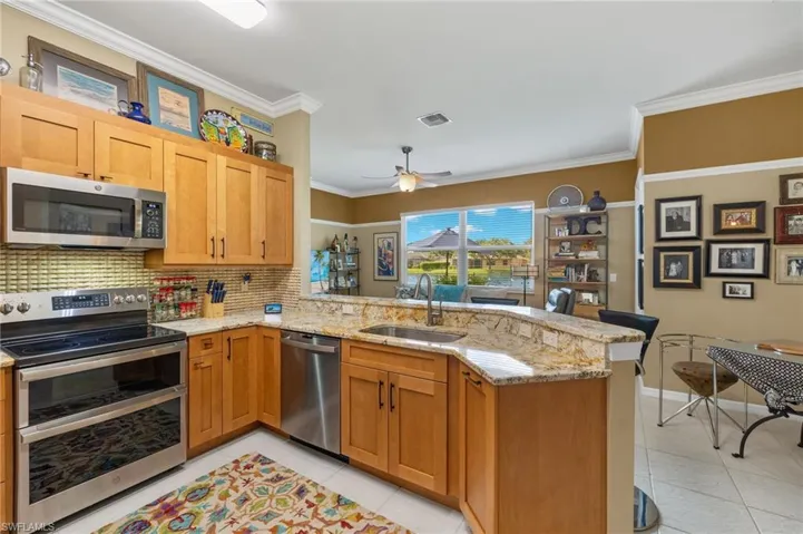Kitchen with ceiling fan, stainless steel appliances, light tile patterned floors, and kitchen peninsula.