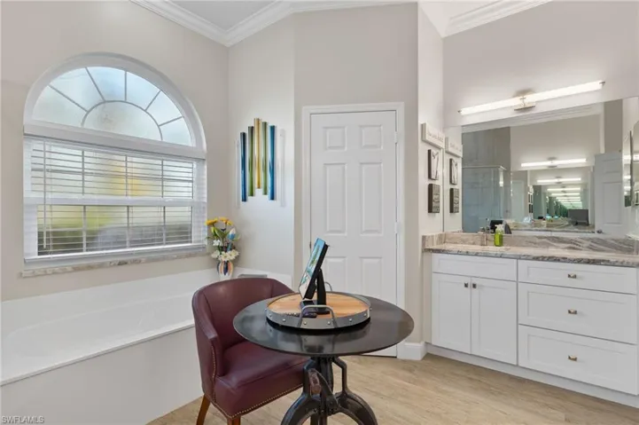 Bathroom featuring vanity, crown molding, hardwood / wood-style flooring, and a bathtub.