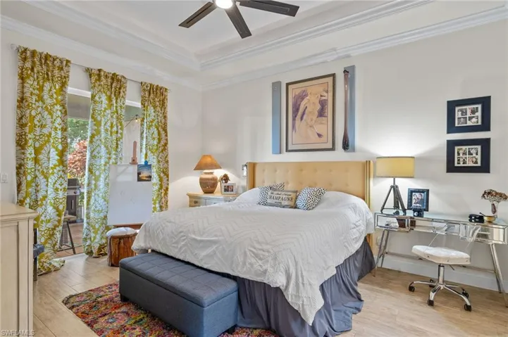 Bedroom featuring light hardwood / wood-style floors, ornamental molding, and ceiling fan.