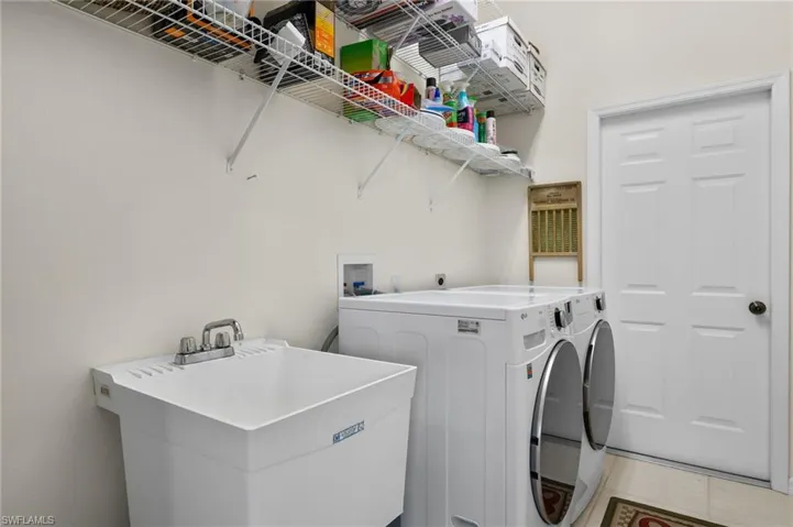 Washroom featuring tile patterned flooring, separate washer and dryer, and sink.