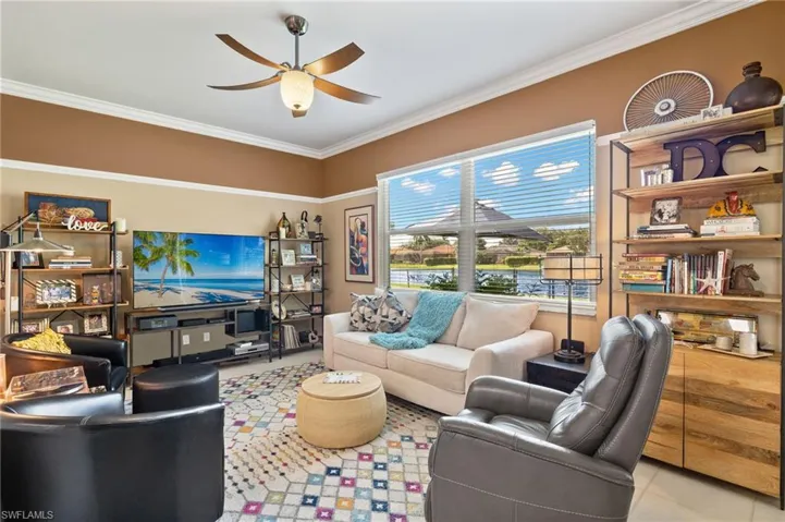 Living room featuring crown molding and ceiling fan, lake view.