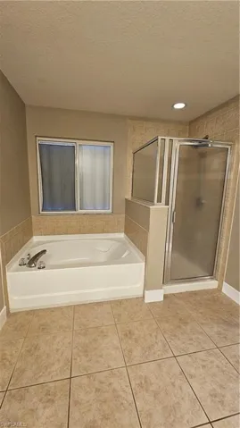 Bathroom with tile patterned flooring, separate shower and tub, and a textured ceiling