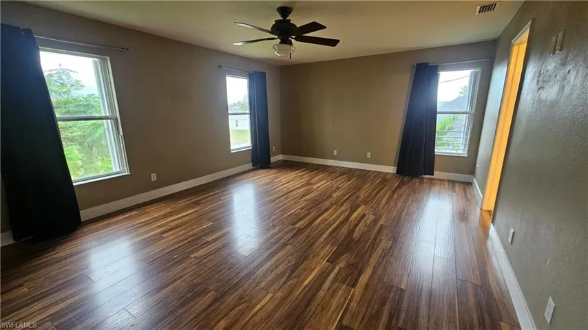 Spare room with plenty of natural light, dark wood-type flooring, and ceiling fan