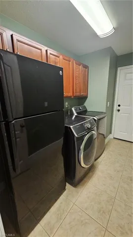 Laundry area featuring light tile patterned floors, cabinets, and washer / dryer