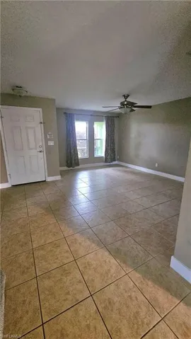 Foyer with ceiling fan, light tile patterned floors, and a textured ceiling