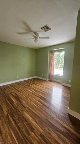 Empty room featuring ceiling fan, dark wood-type flooring, and a textured ceiling