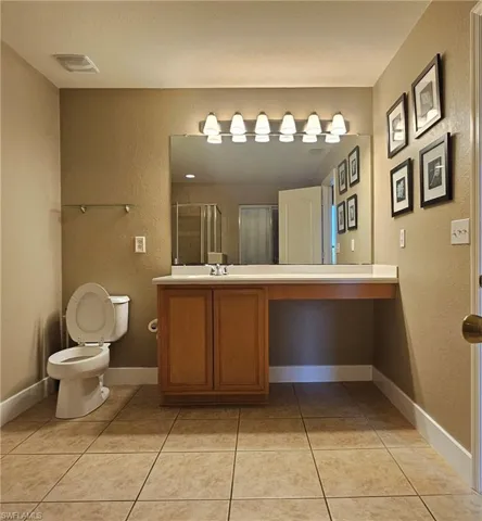 Bathroom with tile patterned floors, vanity, toilet, and an enclosed shower