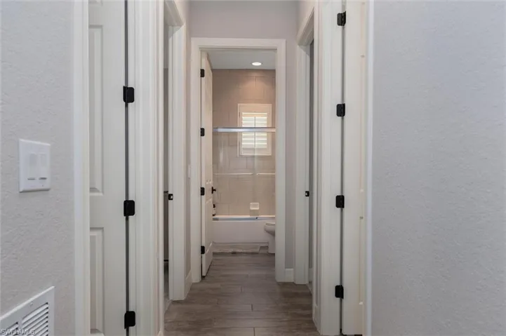 Hallway featuring wood-finish flooring, light grey painted walls, and white trim