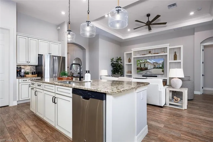 Open-concept living space with a kitchen island featuring a granite countertop and integrated stainless steel dishwasher