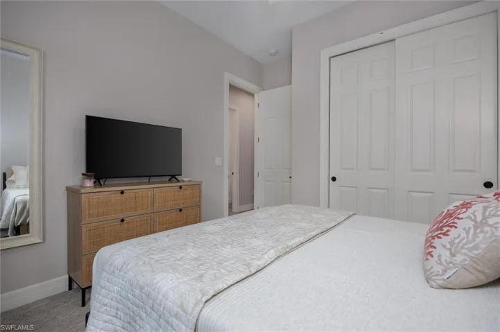 Bedroom featuring neutral wall paint, carpet flooring, and a large sliding closet with panel doors and black hardware