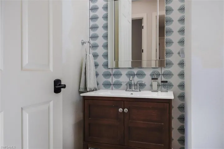 Bathroom vanity featuring a wood-finish cabinet, white countertop, and polished chrome faucet
