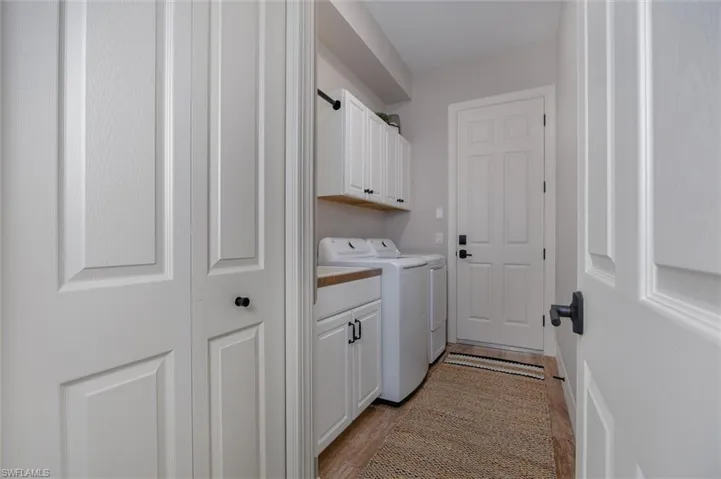 Laundry area featuring white cabinetry, wood-finish countertop, and a light wood-finish flooring