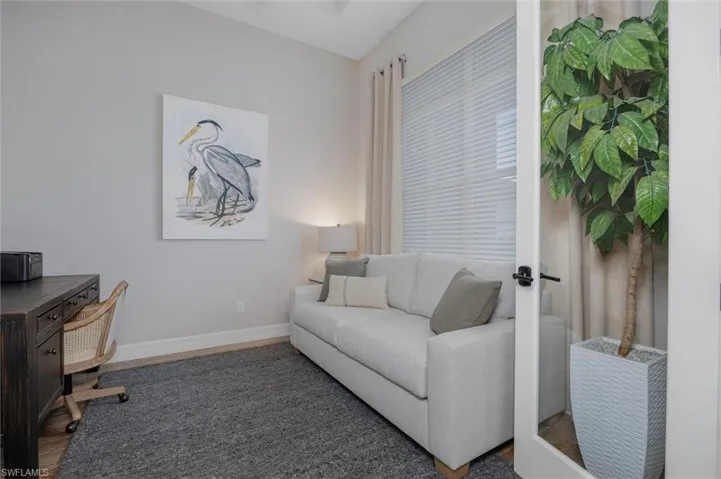 Versatile room featuring wood-finish flooring, a contemporary area rug, and a large window with blinds