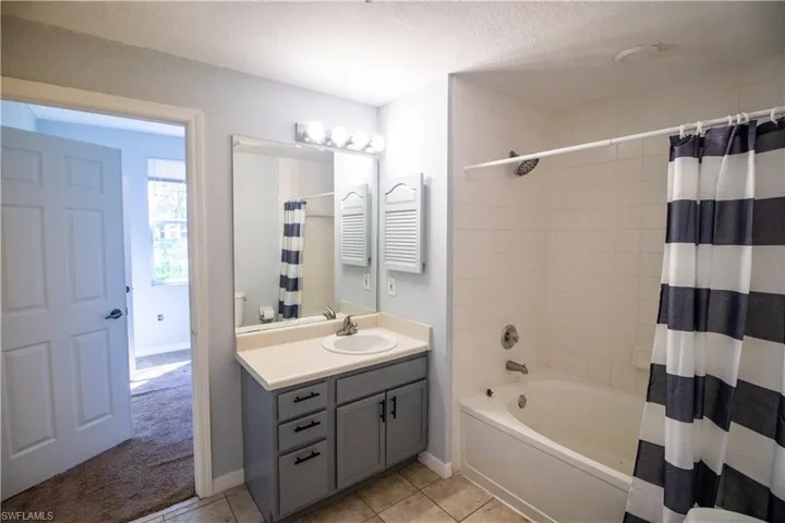 Full bathroom featuring shower / tub combo, tile patterned flooring, a textured ceiling, toilet, and vanity
