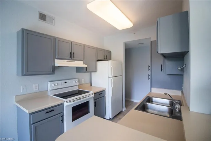 Kitchen featuring sink, white appliances, and light tile patterned floors