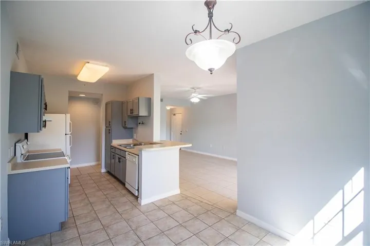 Kitchen with decorative light fixtures, light tile patterned flooring, ceiling fan, and white appliances