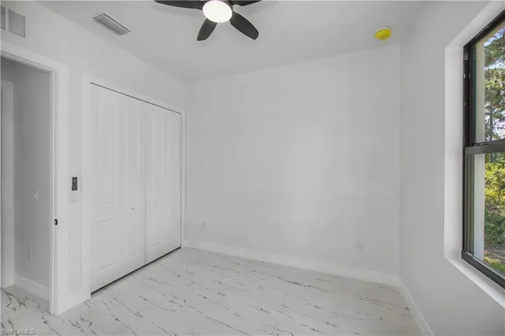 White walls with a black-framed window and a black ceiling fan
