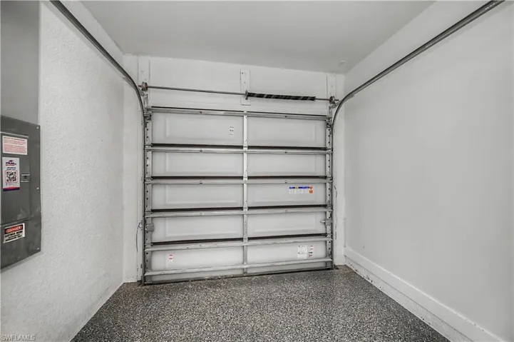 Garage space featuring a roll-up door, speckled flooring, and textured wall finishes