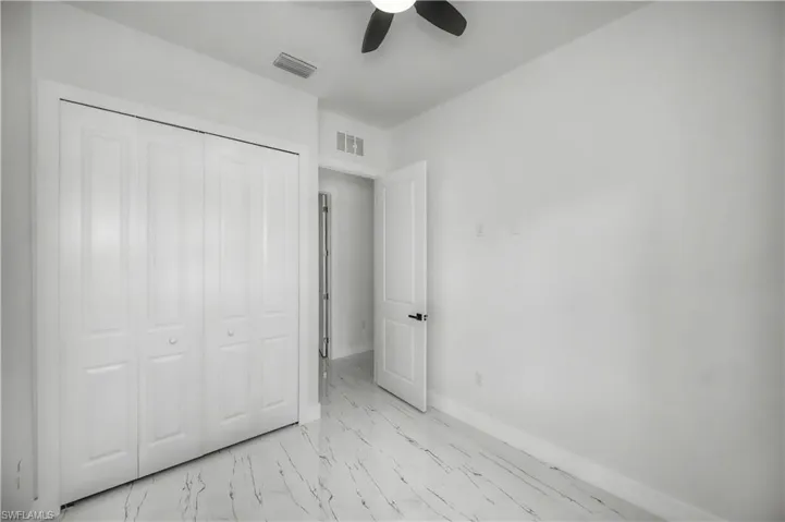 White bifold closet doors, light-toned walls, and a ceiling fan with dark blades