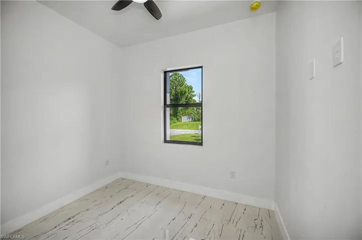 Light-filled room featuring a single window, a ceiling fan, and wood-finish flooring
