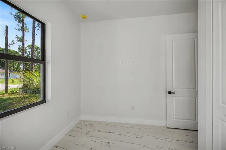 Recessed window with black framing, white walls, and marble-finish flooring
