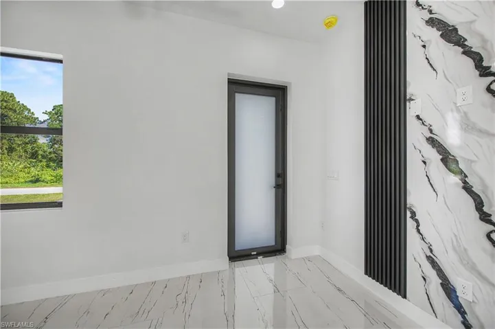 White walls, marble-patterned flooring, and a window with black trim