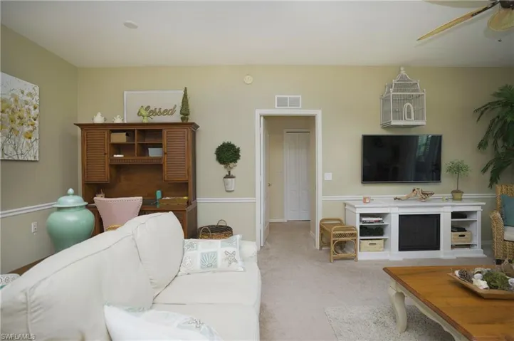 Carpeted living room featuring ceiling fan and a fireplace