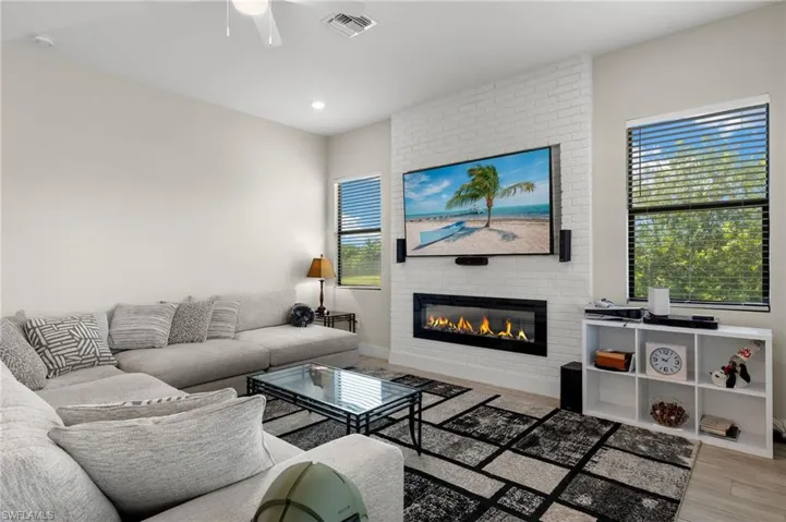 Living room featuring light hardwood / wood-style flooring, a brick fireplace, a wealth of natural light, and ceiling fan