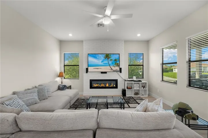 Living room with a fireplace, ceiling fan, and hardwood / wood-style flooring
